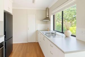 a white kitchen with a sink and a window at Snapper Rocks Ocean view Retreat in Coolangatta