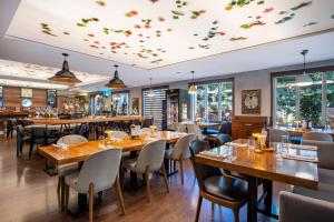 a restaurant with wooden tables and chairs and windows at Mercure Tbilisi Old Town in Tbilisi City