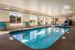 a large swimming pool with blue chairs and windows at Comfort Suites Brunswick - Cleveland Southwest in Brunswick