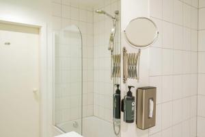 a bathroom with a shower with a mirror and bottles at Aspire Kronprinz, Trademark Collection by Wyndham in Schwäbisch Hall +63 photos