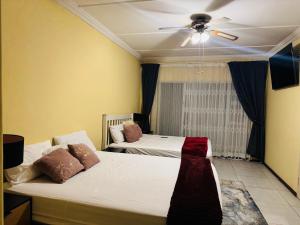 a bedroom with two beds and a ceiling fan at Garden Nest Guest House in Vanderbijlpark