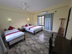 a hotel room with two beds and a window at Hotel Happy Land in Chitwan