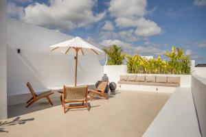 eine Terrasse mit Stühlen und einem Sonnenschirm auf einem Gebäude in der Unterkunft CosyCalm 2bd Villa wRooftop 4 mins Cemagi Beach in Cemagi