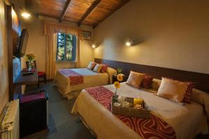 a hotel room with two beds and a television at Hotel de la Cañada Mina Clavero in Mina Clavero