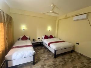 a room with two beds and a table in it at Hotel Happy Land in Chitwan