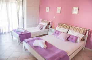 Duas camas num quarto com paredes cor-de-rosa em Studios Konstantina em Ligia