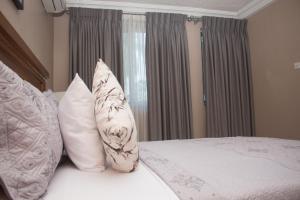 - une chambre avec un lit et des oreillers blancs dans l'établissement Manjaro Suites, à Accra