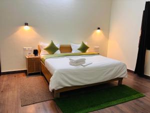 a bedroom with a large bed with green pillows at Jim Corbett Guest House in Jhirna
