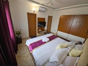 a bedroom with a large bed with towels on it at Broadway Inn in Mysore