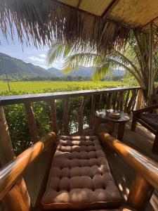 eine Bank auf einer Veranda mit Blick auf ein Feld in der Unterkunft Coconut Minh Tho Homestay in Mai Châu
