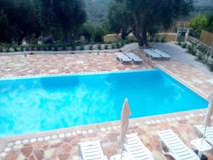 ein großer Pool mit Stühlen und einem Sonnenschirm in der Unterkunft Villa Androniki in Longós