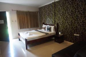 a bedroom with a bed in a room with wallpaper at The Park Nangrong Resort in Nang Rong
