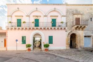 a large white building with green shutters at Palazzo Costantini in San Donato di Lecce