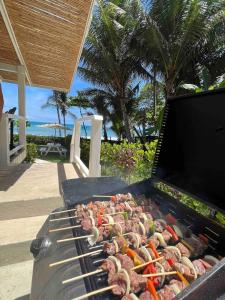 a grill with meat and vegetables on a beach at Backyard Beach House Oceanfront Luxury 5 Bdr in Playa Hermosa