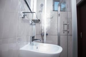 a white bathroom with a sink and a shower at Manjaro Suites in Accra