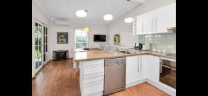 a large white kitchen with white cabinets and wooden floors at Tompson Apartment in Wagga Wagga