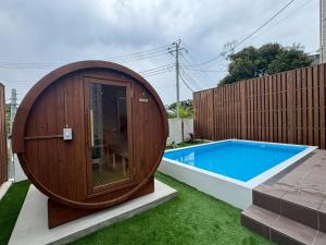 ein rundes Holzgebäude neben einem Swimmingpool in der Unterkunft Comlien Villa Resort in Tateyama