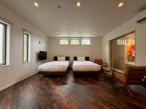 2 Betten in einem Zimmer mit Holzböden und Fenstern in der Unterkunft Comlien Villa Resort in Tateyama