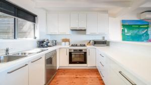 a white kitchen with white cabinets and a sink at '33 Degrees - Stunning Views' by HolidayCo in Hardys Bay +16 photos