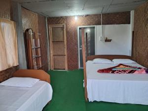um quarto com duas camas e um piso verde em Dibru-Saikhowa Eco Camp  mais 6 fotografias