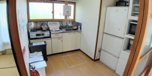 a small kitchen with a refrigerator and a sink at 布施温泉ステイ　ウエスト in Saku