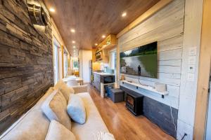 a living room with a couch and a flat screen tv at Spa & River view - Le Conteneur Cache in Saint-Just-de-Bretenières