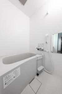 een witte badkamer met een wastafel en een spiegel bij AROMA in Sapporo