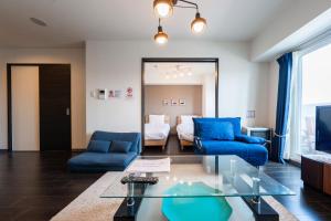 een woonkamer met blauwe stoelen en een glazen tafel bij AROMA in Sapporo