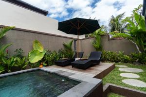 an umbrella and chairs next to a swimming pool at Villa Alam Kita in Ubud