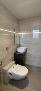 een badkamer met een wit toilet en een wastafel bij Eco Wind in Lonavala