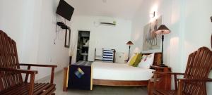 a bedroom with a bed and two wooden chairs at Ceylonika Rest in Bentota