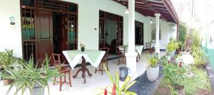 a patio with a table and chairs and potted plants at Ceylonika Rest in Bentota