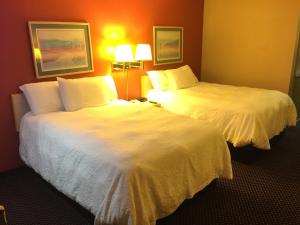 two beds in a hotel room with white sheets at Americas Best Value Inn - Garden City in Garden City