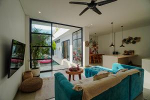 タナロットにある'Villa Vivid' 2BR Bohemian, 5 min to Kedungu Beachの青いソファとキッチンのあるリビングルーム