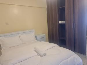 una cama blanca con sábanas y almohadas blancas en Lawrence place, en Nairobi
