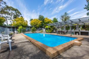 a swimming pool in a yard with a patio at Sky Rider Motor Inn in Katoomba