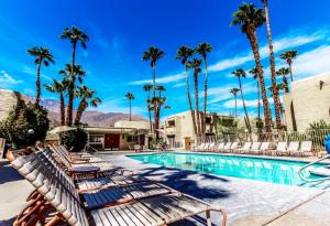 a resort pool with lounge chairs and palm trees at Desert Vacation Villas in Palm Springs
