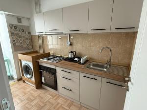 a kitchen with white cabinets and a sink and a stove at City Centre Craiova in Craiova