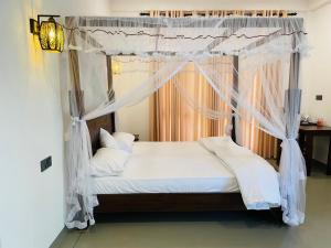 a bedroom with a canopy bed with white sheets and pillows at The Arch View in Habaraduwa Central