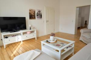 een woonkamer met een televisie en een witte tafel bij Ferienwohnung Villa Else in Bad Neuenahr-Ahrweiler