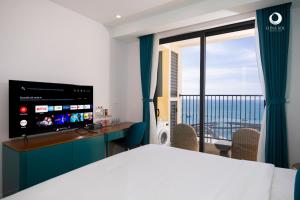 a hotel room with a bed and a desk and a window at Solara Apartment Firework & Sunset View in Phú Quốc