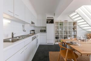 a kitchen with white cabinets and a wooden table at Seahouse by BLOSS, appartement met magistraal zeezicht met 2 terrassen in Wenduine