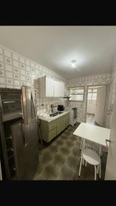 eine Küche mit einem Kühlschrank und einem Tisch darin in der Unterkunft Apartamento Guarujá in Guarujá