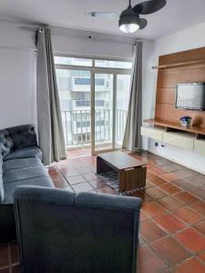 ein Wohnzimmer mit Sofa und Fernseher in der Unterkunft Apartamento Guarujá in Guarujá
