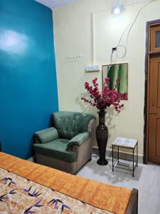 a living room with a green couch and a vase with flowers at Hotel Shanti rest house - शांति विश्राम गृह Gaya in Gaya