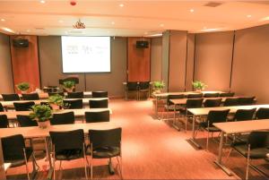 una sala de conferencias con mesas y sillas y una pantalla de proyección en James Joyce Coffetel·Shijiazhuang Economic and Technological Development Zone Chuangye Road, en Shijiazhuang