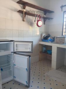 a kitchen with a refrigerator and a clock on the wall at Dannys&nickson holiday homes in Watamu