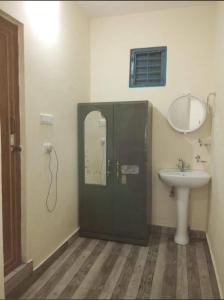 uma casa de banho com um lavatório e uma porta com um espelho em Dibru-Saikhowa Homestay em Tinsukia