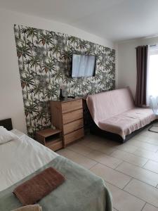 a bedroom with a bed and a couch and a flat screen tv at Eleven Pokoje in Gdynia