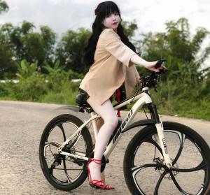 Une jeune fille à vélo sur une route dans l'établissement Homestay Timi, à Nha Trang